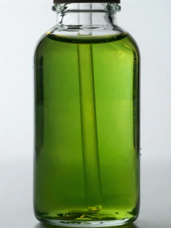 Avokadoöljyä pienessä pullossa ja kulhossa vaalealla, neutraalilla taustalla