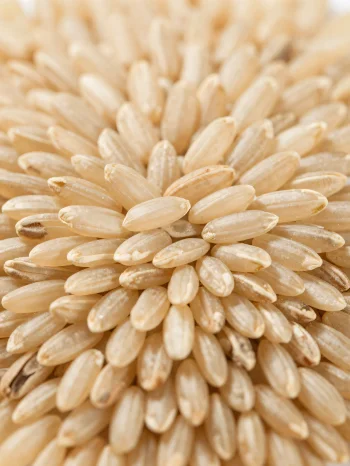 Raakoja täysjyväriisin jyviä maalaiskulhossa keittiötasolla