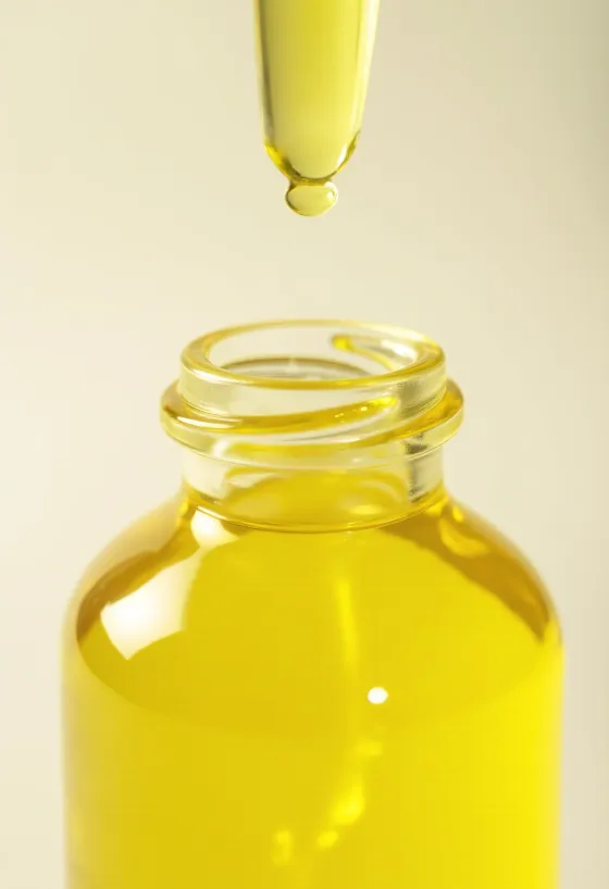 Sitruunaöljyä pienessä pullossa, vieressä tuoreita sitruunaviipaleita ja kuoriraastetta