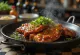 Kimchi's Galbi paistettuja naudanlihaviipaleita, koristeltu kevätsipulilla ja seesaminsiemenillä