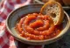 Makea mojo rojo -kastike kulhossa, ympärillä paahdettuja paprikanpaloja