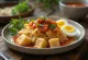 Lontong sambal-kastikkeella, tuoreella kananmunalla tarjoiltuna lautasella
