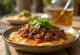 Chilaquiles con carne molida – jauhelihalla, punaisella kastikkeella, juustolla ja smetanalla tarjoiltuna