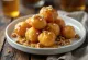 Zeppole hunajalla ja saksanpähkinöillä, kullanruskeita leivonnaisia hunajalla tarjoiltuna